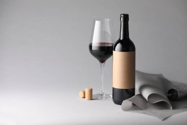 Tirbuşonlu, mantarlı ve gri arkaplanlı bir şişe ve bir bardak şarap. Metin için boşluk