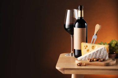 Kahverengi arka plana karşı ahşap masada lezzetli şarap ve atıştırmalıklar. Metin için boşluk