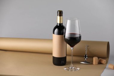 Tirbuşonlu, mantarlı ve gri arkaplanlı bir şişe ve bir bardak şarap. Metin için boşluk