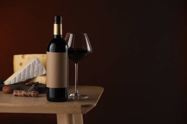 Lezzetli şarap ve peynir, ahşap masada, kahverengi arkaplanda. Metin için boşluk