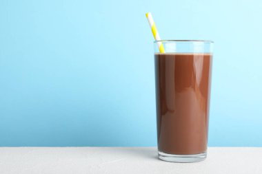 Açık mavi arka planda beyaz masada lezzetli çikolatalı süt. Metin için boşluk