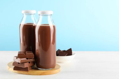 Lezzetli çikolatalı süt ve beyaz masadaki parçalar açık mavi arka plana karşı. Metin için boşluk