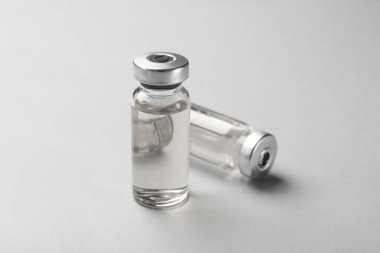 Gri arka planda cam şişelerde Hepatit aşısı, yakın plan.