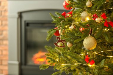 Evdeki şöminenin yanında at oyuncağı, diğer süsler ve festival ışıklarıyla süslenmiş güzel bir Noel ağacı, yakın çekim. Metin için boşluk