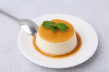 Beyaz masada servis edilen karamel soslu lezzetli puding, yakın plan.