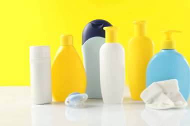 Bebek kozmetik ürünleri, çoraplar ve emzik sarı arka planda