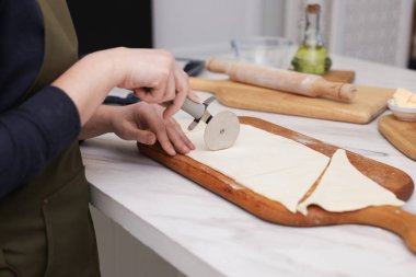 Açık mermer masada hamuru kesen kadın, yakın plan. Kruvasan yapıyorum.