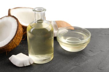 Organik hindistan cevizi pişirme yağı ve siyah masada beyaz arka planda taze meyveler.