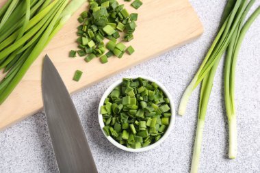 Taze yeşil soğan ve bıçak açık gri masada, düz yatıyordu.