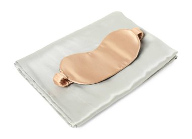 Beyaz arka planda ipek çarşaflar ve uyku maskesi.