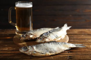 Kurutulmuş hamamböceği balığı ve bir bardak bira ahşap masada, yakın plan.