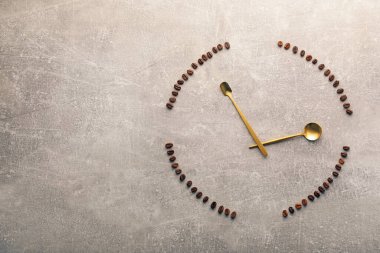 Kahve çekirdekleri ve kaşıklar gri masada saati temsil ediyor. Metin için boşluk