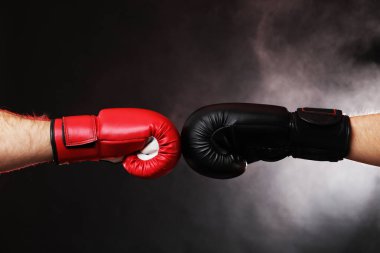 Boks eldivenli adamlar karanlık arka planda dumanla savaşıyor.