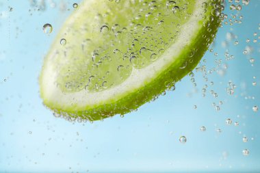Kireç dilimli soda, açık mavi arkaplan, yakın plan.