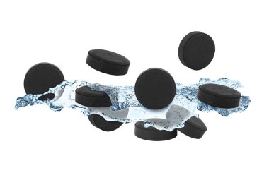 Aktif kömür hapları ve beyaz arka planda su sıçramaları. Etkin sorbent