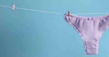 Çamaşır ipinde açık mavi arka planda asılı güzel iç çamaşırları. Kamera sağa hareket ediyor
