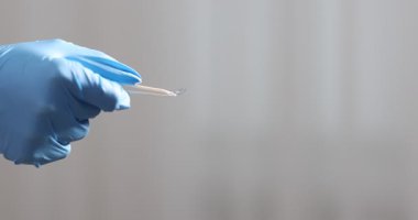 Oftalmolog elinde cımbızla kontak lensi tutuyor ve hastaya veriyor, yakın plan.