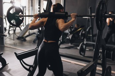 Spor salonunda halterle antreman yapan atletik bir kadın.
