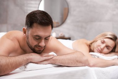 Spa salonundaki masaj masalarında yatan çift, seçici odak