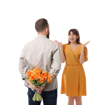 Adam beyaz arka planda sevgili karısına güzel laleler saklıyor.