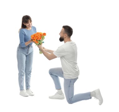 Adam beyaz arka planda sevgili karısına güzel laleler sunuyor.