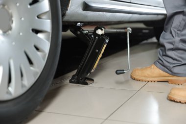 Makas kriko ile kaldırılan araba. Servis istasyonunda otomatik tamirci tamir aracı, kapatılıyor