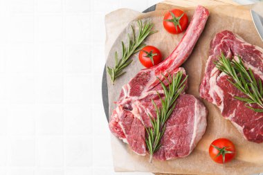 Çiğ et parçaları, biberiye ve domatesler beyaz fayanslı masa, üst manzara. Metin için boşluk