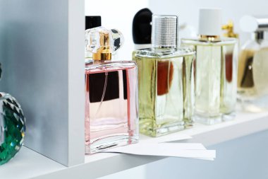 Dükkandaki raflarda farklı parfüm şişeleri ve parfümler var.