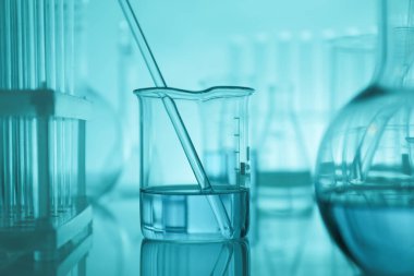 Aynanın yüzeyinde turkuaz arka plana karşı laboratuvar camı var.