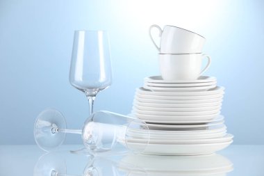 Different clean dishware on light blue background