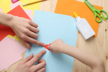 Anne ve kızı ahşap masada el yapımı tebrik kartı yapıyorlar.