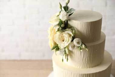 Bulanık arka planda çiçeklerle süslenmiş lezzetli düğün pastası, yakın plan. Metin için boşluk