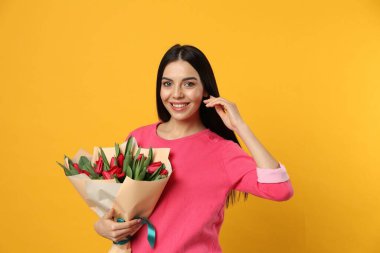 Sarı arka planda kırmızı lale çiçekli mutlu kadın. 8 Mart kutlamaları