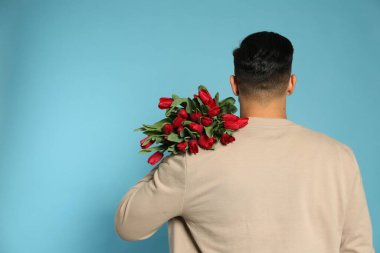 Açık mavi arka planda kırmızı lale çiçekli adam, mesaj için yer var. 8 Mart kutlamaları