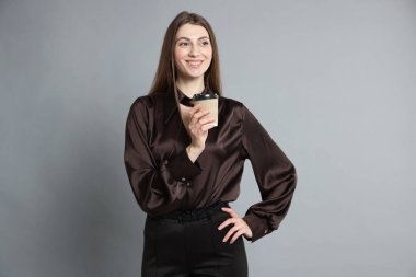 Gri arka planda şık giyinmiş güzel bir kadın.