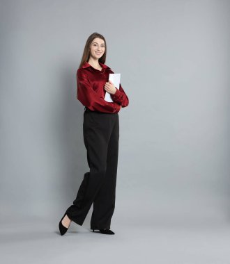 Gri arkaplanı olan şık giyinmiş güzel bir kadın.