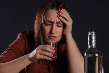 Alkol bağımlılığı. Sefil kadın, karanlıkta votka içiyor.