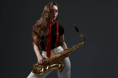 Gri arka planda saksafonu olan profesyonel bir müzisyen.