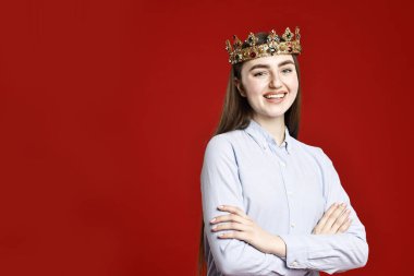 Koyu kırmızı arka planda zarif taç giymiş gülümseyen kadın. Metin için boşluk
