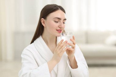 Arka planda bir bardak kolajen suyu olan gülümseyen kadın.