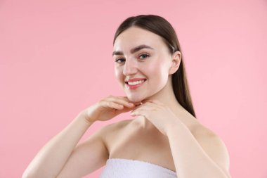 Pembe arka planda sağlıklı cildi olan gülümseyen kadın.