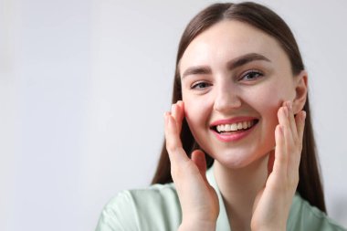 Gri arka planda sağlıklı cildi olan gülümseyen bir kadın. Metin için boşluk