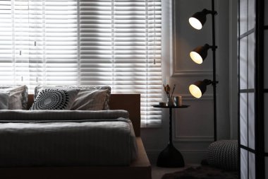 Şık bir odada yatağın yanında lamba. İç tasarım