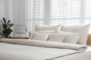 Şık bir odada yumuşak çarşafları olan rahat bir yatak, yakın çekim. İç tasarım