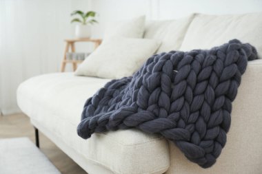 Odadaki kanepede örülmüş merino yün ekose.