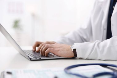 Hastane masasında dizüstü bilgisayarda çalışan profesyonel bir doktor.