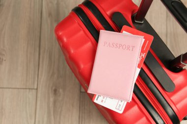 Biletli pasaport ve yerde kırmızı bavul, üst manzara. Metin için boşluk