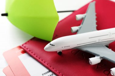 Seyahat sigortası. Uçak modeli, pasaport, küçük şemsiye ve beyaz tahta masa üzerindeki biletler, yakın plan.