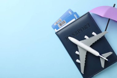 Seyahat sigortası. Uçak modeli, pasaport, küçük şemsiye ve açık mavi arka planda biletler. Metin için boşluk