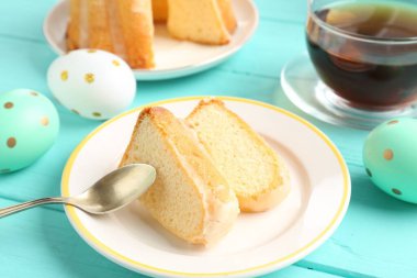 Lezzetli kek parçaları, paskalya yumurtası ve çay açık mavi ahşap masa, yakın plan.